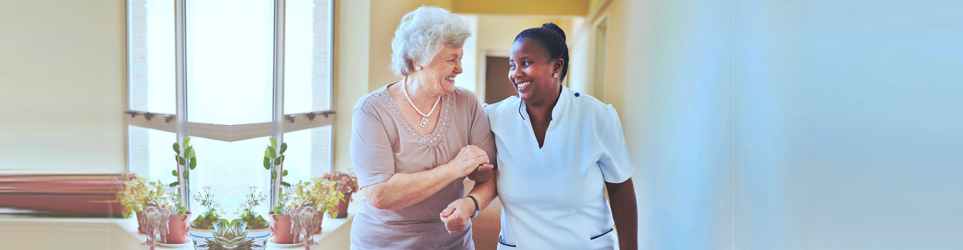 caregiver and senior woman having a conversation while walking at the hallway