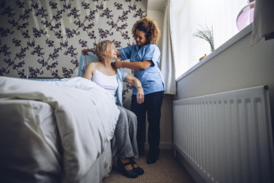 caregiver helping the elder woman get dressed