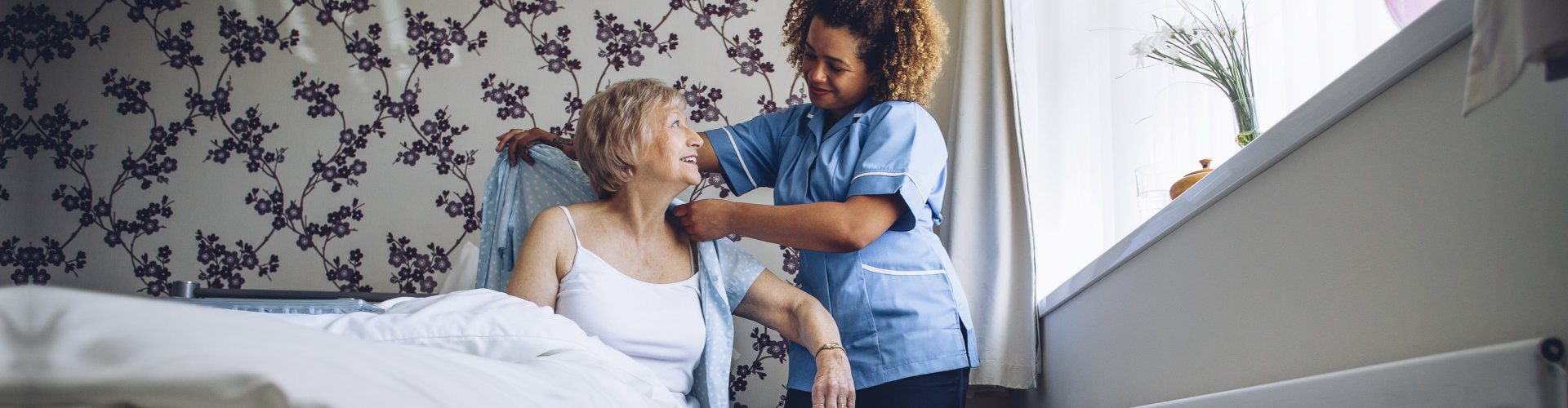 caregiver helping the elder woman get dressed