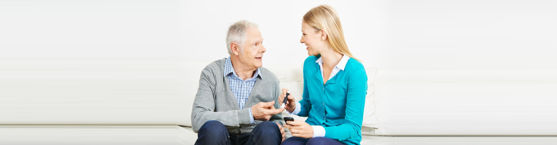 caregiver monitoring the blood sugar level of senior man